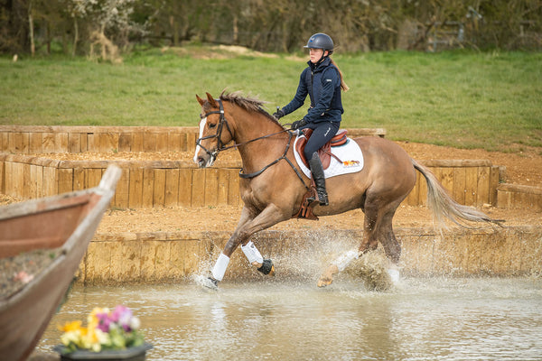 Horse cantering through water wearing Equilibrium Tri-Zone Impact Sports Boots in White