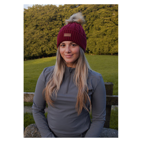 Lady wearing Cameo Cable Knit Bobble Hat in plum